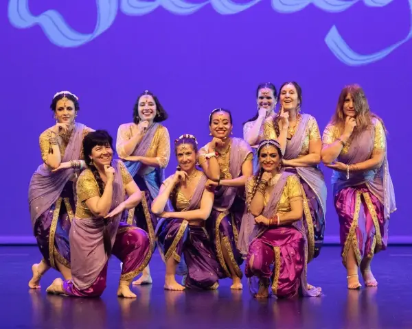 Un grupo de mujeres sonríe y posa con trajes vibrantes, listas para una fiesta bollywood.