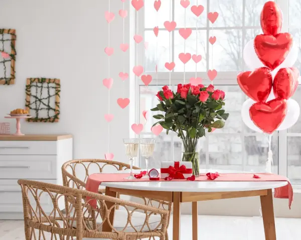 Mesa romántica con rosas, globos en forma de corazón y copas. ¡Perfectas ideas decoración San Valentín!