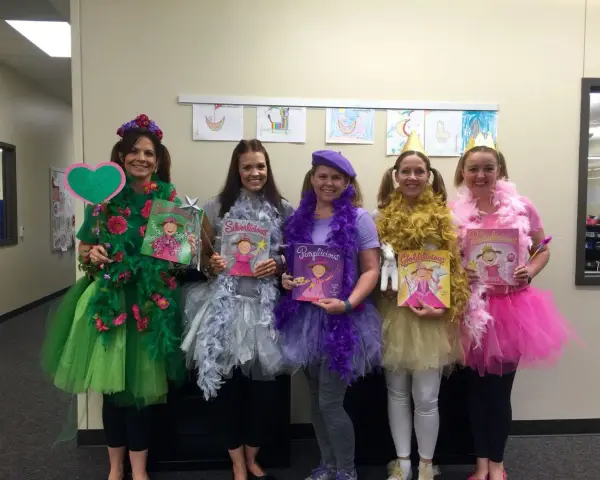 Cinco mujeres con disfraces caseros inspirados en "Ricitos de Oro" y los osos, cada una representando un color: verde, plateado, morado, dorado y rosa.