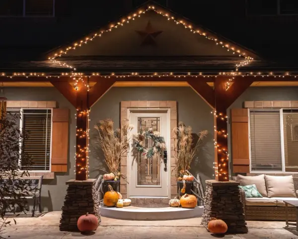 Encantadora decoración Halloween exterior casera con calabazas, luces cálidas y un porche acogedor.