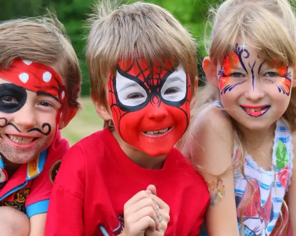 Niños con pintacaras de pirata, Spider-Man y mariposa sonriendo.