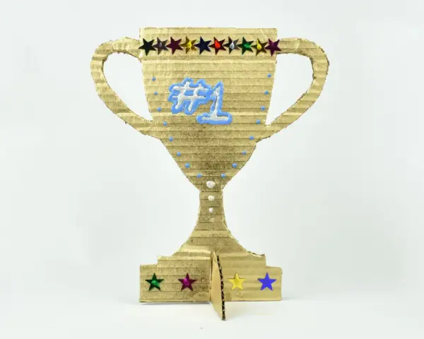 Trofeo de cartón dorado, ideal para hacer trofeos personalizados. Luce un "#1" azul y estrellas de colores.