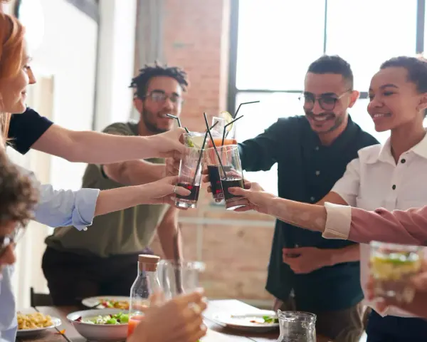 Grupo de amigos brindando con bebidas, inspirando temáticas para juegos de mesa y celebraciones.