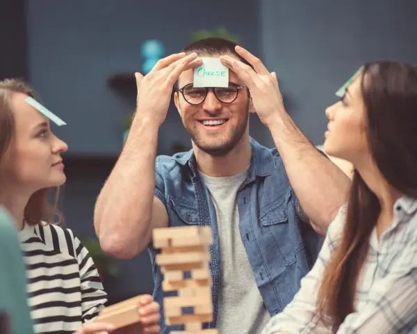 Amigos jugando a "adivina la palabra" en su frente, parte de juegos para fiestas adultos.