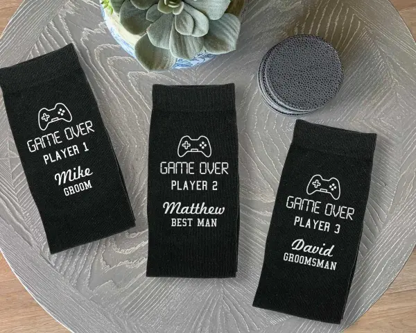 Tres calcetines negros personalizados con temática de videojuegos para boda, con nombres y roles.