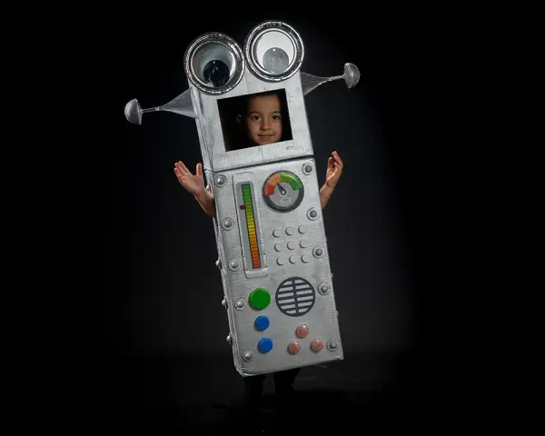 Niño con un divertido disfraz robot casero, con ojos saltones y panel de control. ¡Listo para la aventura!