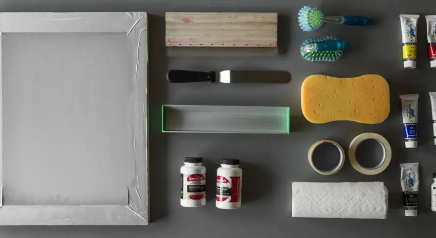 Marco de serigrafía, rasquetas, esponja, cintas, papel, cepillos y tubos de pintura acrílica, todo listo para empezar con los materiales serigrafia.
