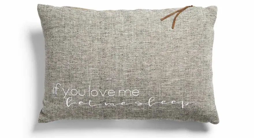 Cojines con frases: uno gris con "if you love me let me sleep" bordado en blanco y un detalle de cuero.