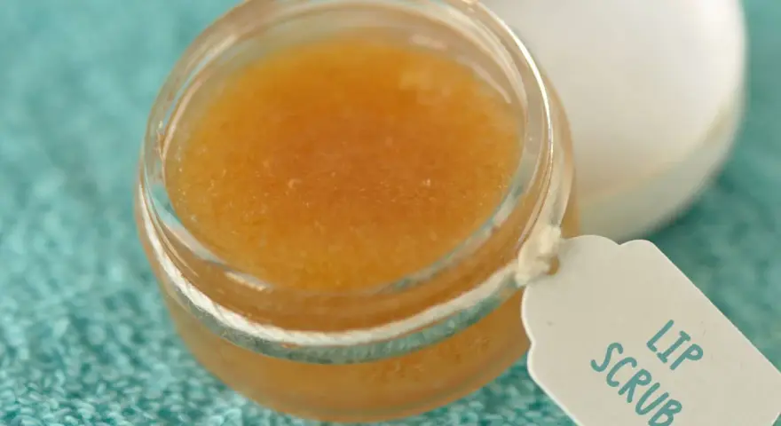 Un tarro de exfoliante de labios casero con etiqueta "Lip Scrub" sobre una toalla turquesa.