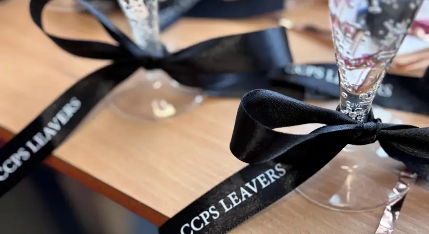 Copas de champán con lazos personalizados negros con el texto "CCPS LEAVERS" para una celebración especial.
