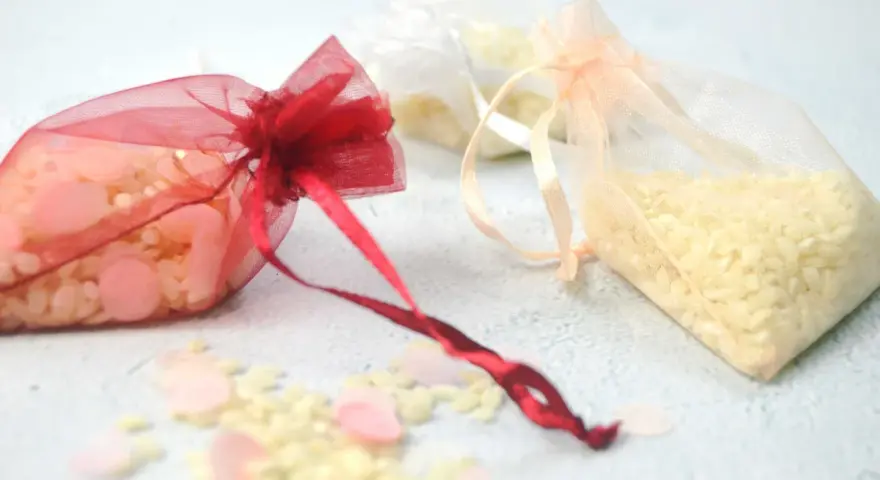 Bolsitas de organza rojas, blancas y melocotón llenas de arroz, listas para usarse como recuerdo. Ideas para como hacer bolsitas de arroz para bodas.