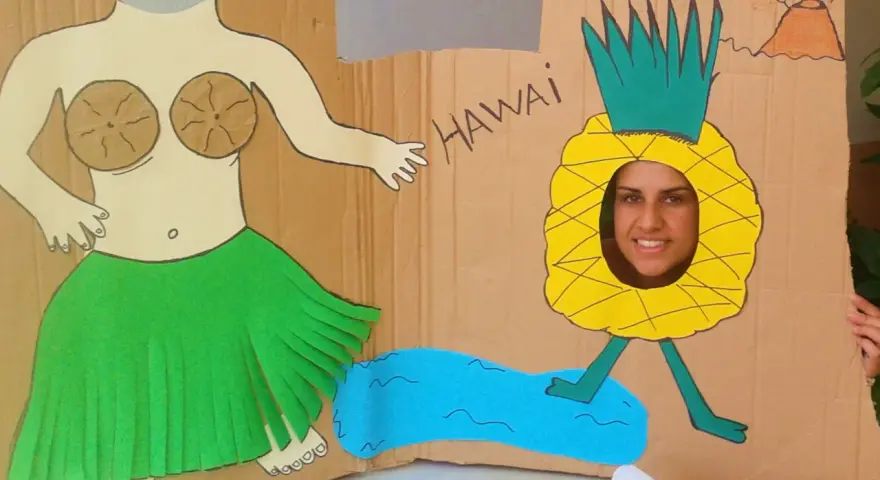 Divertido photocall hawaiano casero con una figura de bailarina y una piña con cara sonriente. ¡Perfecto para unas fotos tropicales!