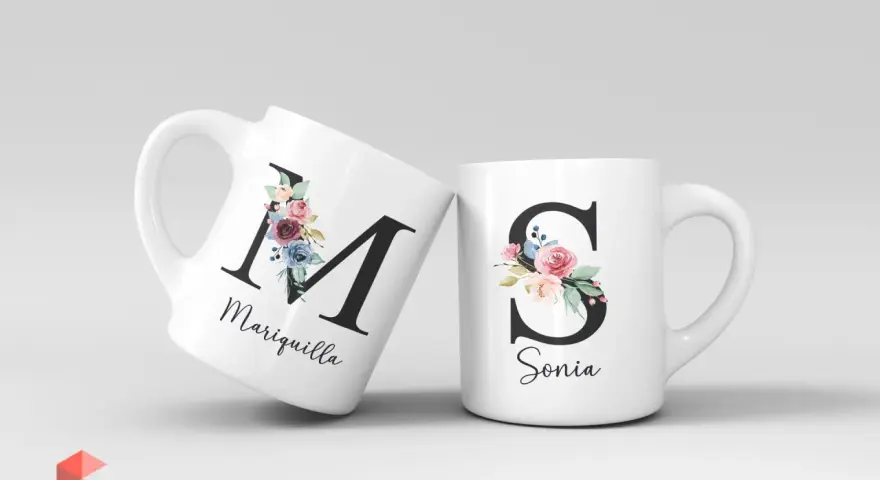Dos tazas blancas con iniciales decoradas con flores. Una tiene la "M" de Mariquilla, la otra la "S" de Sonia.