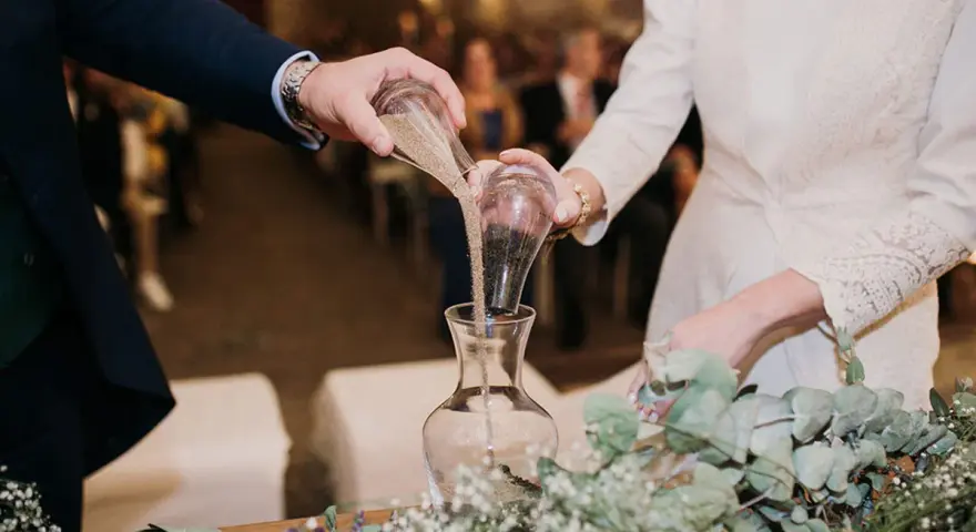 Manos unidas en el ritual de la arena boda, mezclando sus vidas en un solo recipiente.