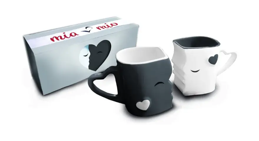 Dos tazas de amor, una negra y otra blanca, con forma de rostros que se miran. La caja dice "mia & mio".