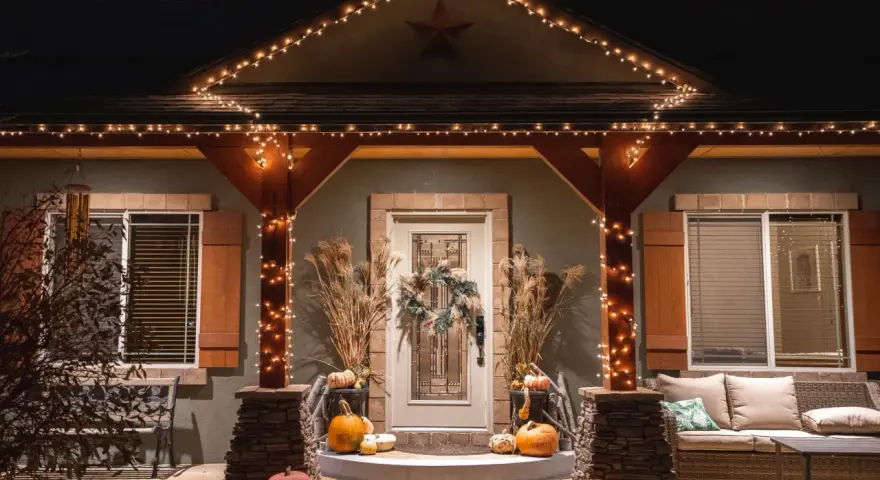 Encantadora decoración Halloween exterior casera con calabazas, luces cálidas y un porche acogedor.