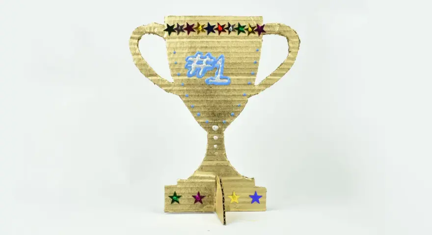 Trofeo de cartón dorado, ideal para hacer trofeos personalizados. Luce un "#1" azul y estrellas de colores.
