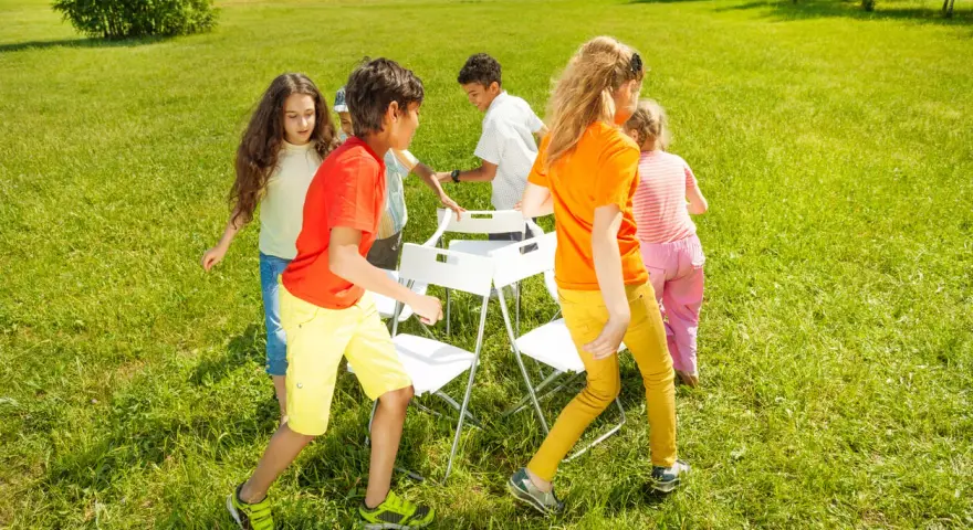 Niños jugando a las sillas musicales, uno de los 20 juegos para fiestas infantiles.
