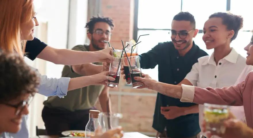 Grupo de amigos brindando con bebidas, inspirando temáticas para juegos de mesa y celebraciones.