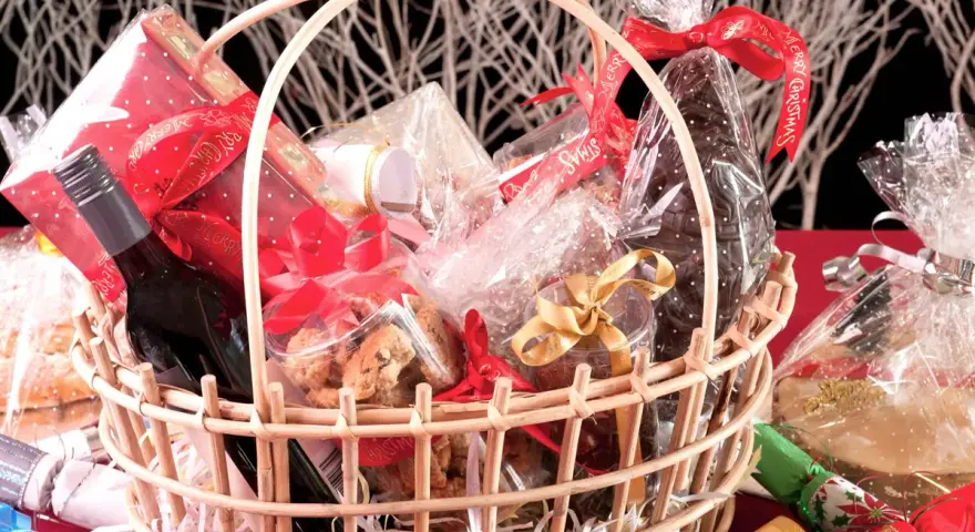 Canasta llena de dulces, galletas, una botella de vino y adornos navideños. ¡Perfecta para ideas para rifar!