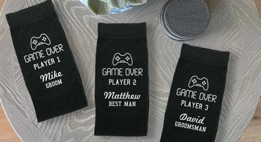 Tres calcetines negros personalizados con temática de videojuegos para boda, con nombres y roles.