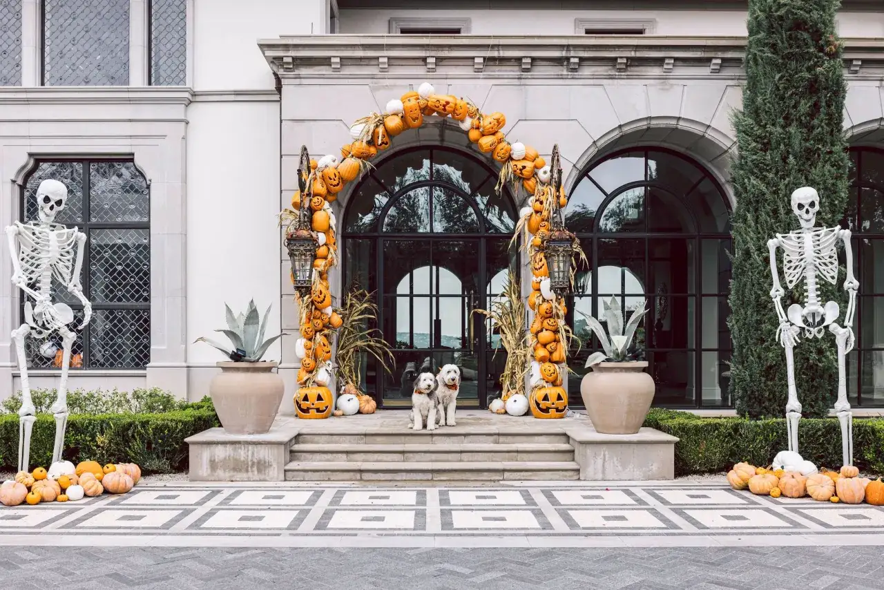 Espectacular decoraci&oacute;n Halloween exterior casera con esqueletos, calabazas y dos perros guardianes.