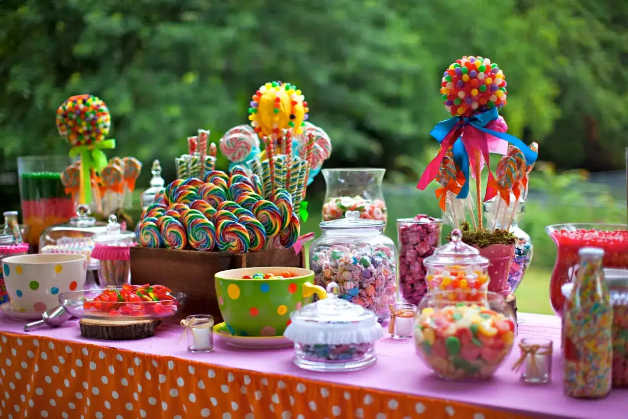 Mesa de fiesta tem&aacute;tica colores, llena de piruletas, caramelos y dulces de todos los colores.