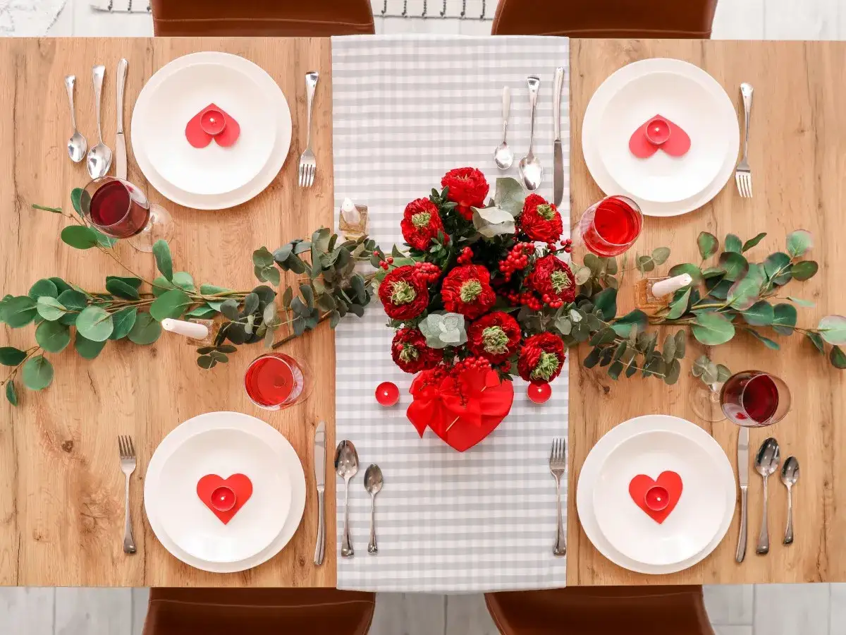 Mesa romántica con velas en forma de corazón, flores rojas y copas de vino. ¡Perfectas ideas decoracion san valentin!