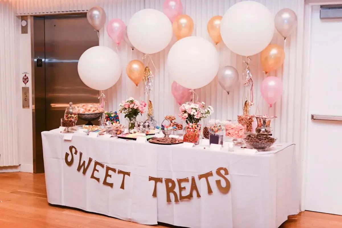Mesa de dulces con globos y un cartel