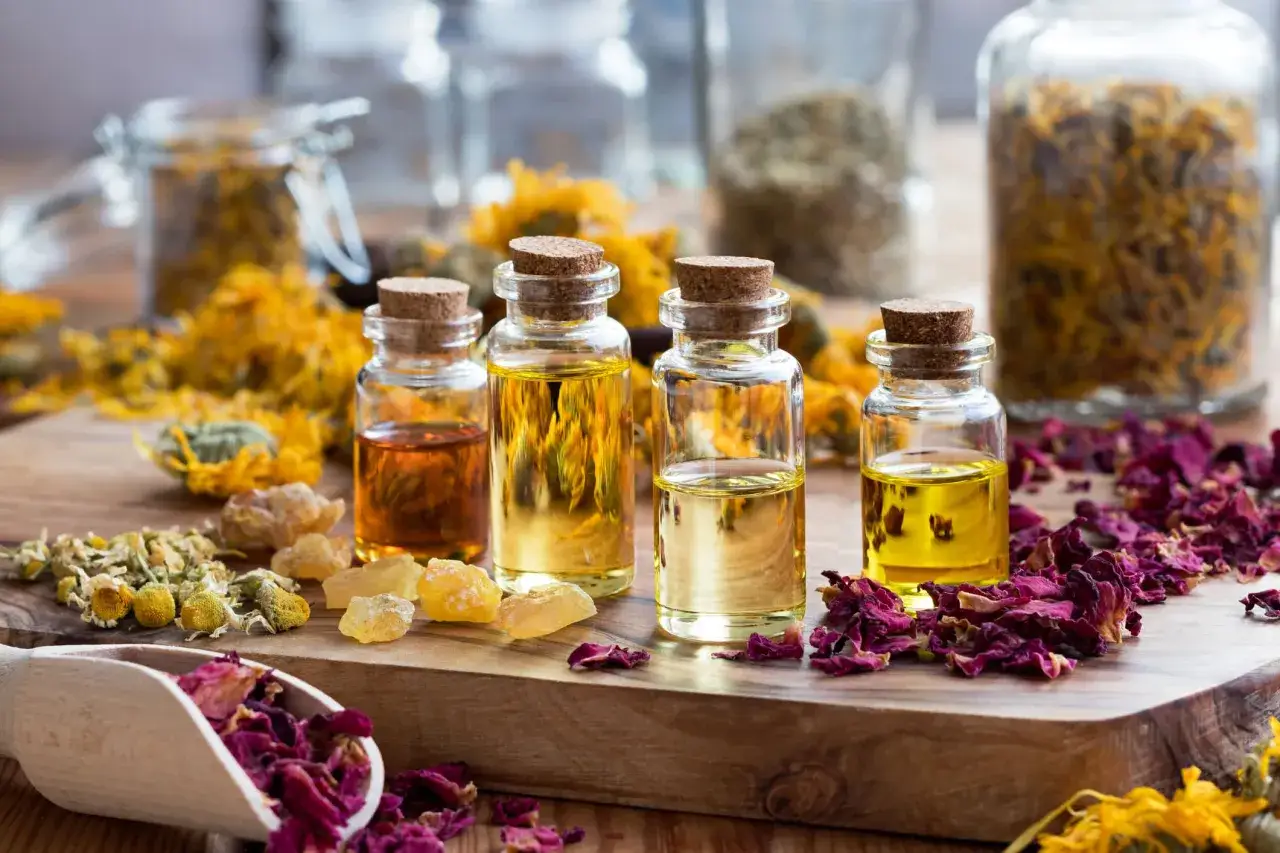 Botellas con aceites esenciales y pétalos de rosa, manzanilla y caléndula. Ideas para como hacer esencias aromaticas caseras.