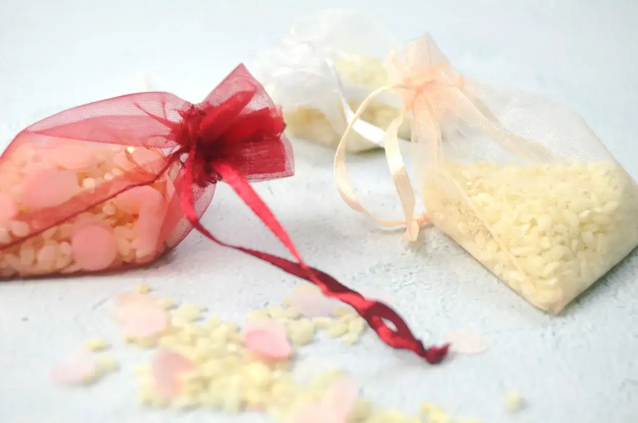 Tres bolsitas de organza con arroz, una roja, una blanca y una melocot&oacute;n. Ideas para como hacer bolsitas de arroz para bodas.