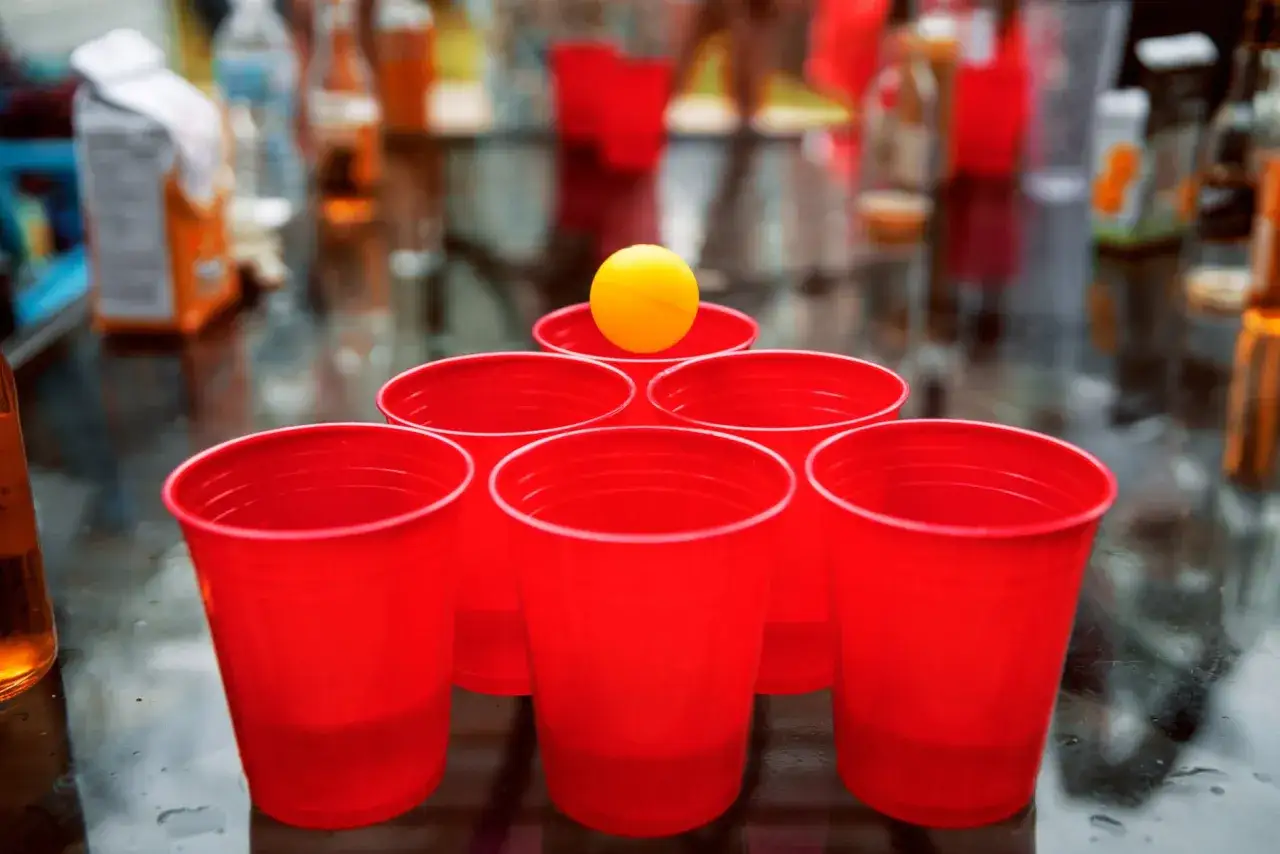 Una pirámide de vasos rojos y una pelota amarilla, lista para divertidos juegos para fiestas adultos.