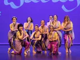 Un grupo de mujeres sonríe y posa con trajes vibrantes, listas para una fiesta bollywood.
