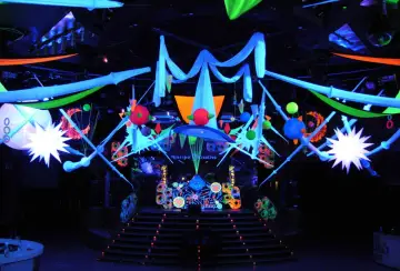 Decoración vibrante para una fiesta futurista, con luces neón, telas colgantes y estructuras geométricas que crean un ambiente de otro mundo.
