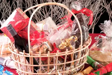 Canasta llena de dulces, galletas, una botella de vino y adornos navideños. ¡Perfecta para ideas para rifar!